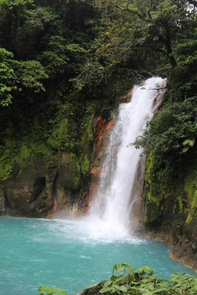 Waterfall cascading into blue river.